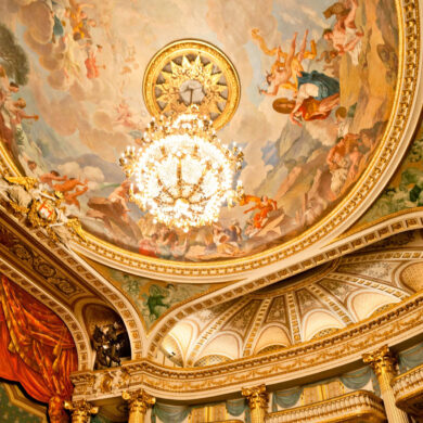 Photographie en contre-plongée du plafond de la salle de spectacle avec fresque et décorations